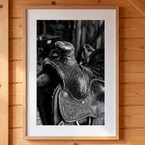 Black and white close up of a western saddle with worn leather and detailed craftsmanship, ranch wall art.
