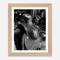 Black and white close up of a western saddle with worn leather and detailed craftsmanship, ranch wall art.