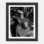 Black and white close up of a western saddle with worn leather and detailed craftsmanship, ranch wall art.